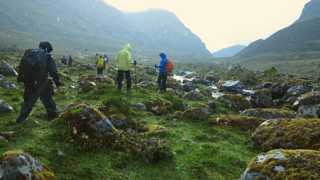 Group of hikers trekking through the Andean mountains in the rain, experiencing Peru’s rugged landscapes - Inka Trail Peru.info