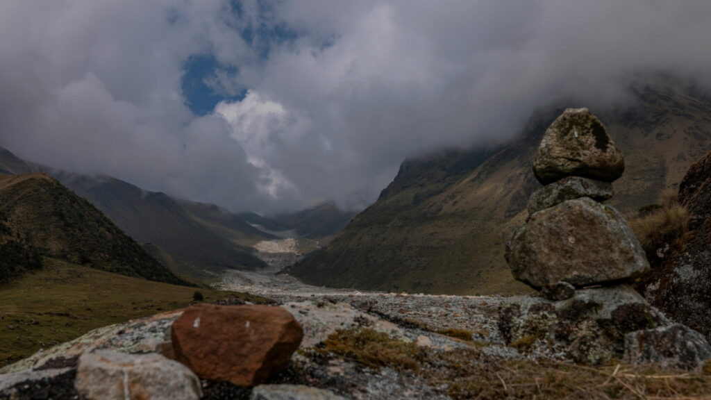 Misty Andean valley with a stacked stone cairn, marking the trail in Peru’s highlands - Inka Trail Peru.info