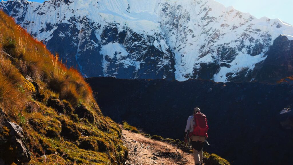 Lone hiker trekking through the Andean mountains towards the majestic Salkantay peak in Peru - Inka Trail Peru.info