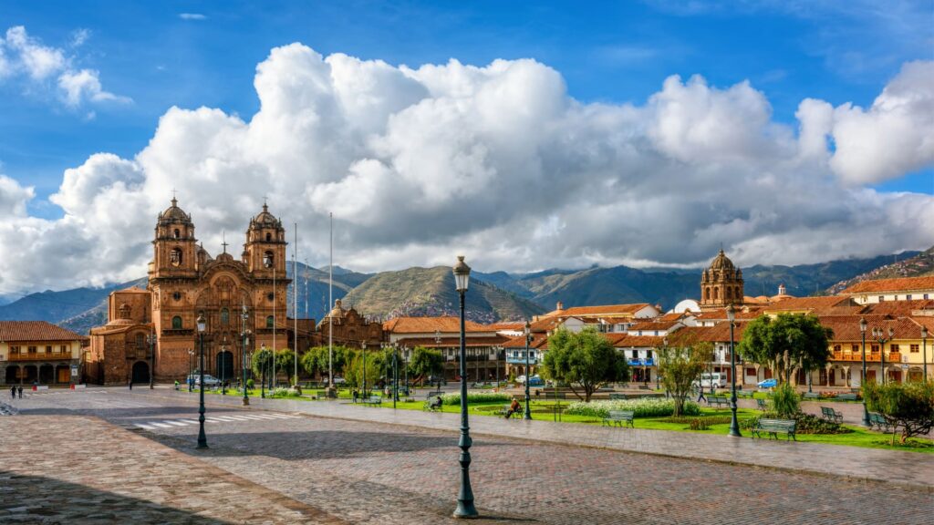Panoramic view of Cusco’s Main Square with colonial churches, red rooftops, and mountains in the background - Inka Trail Peru.info