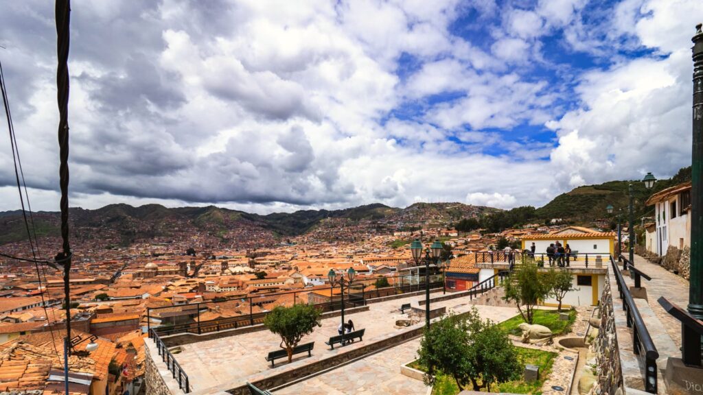 Panoramic view of Cusco city with colonial rooftops and dramatic skies seen from an overlook - Inka Trail Peru.info